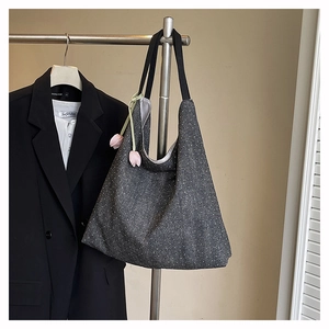 Detail of grey dotted denim tote bag with pink tulip pendant and black strap on hanger