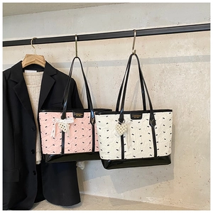 Détail du sac cabas rose et blanc à motifs nœuds avec breloque cœur en perles