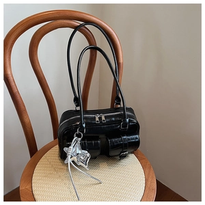 Détail du sac Boston noir brillant avec breloque étoile argentée et poches à motif croco