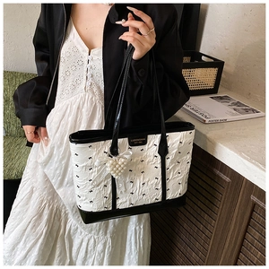 Détail du sac cabas blanc plissé avec nœuds noirs et grand pendentif cœur en perles