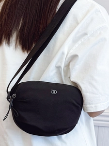 Minimalist black nylon half-moon crossbody bag with silver logo and wide textile strap