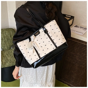 Détail du sac cabas rose avec imprimé nœuds noirs et pendentif en dentelle et perles