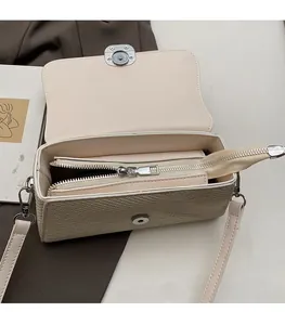 Detail view of the beige woven square bag showing internal dual compartments and silver zipper