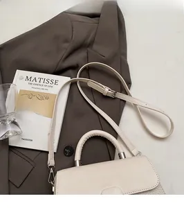 Detail view of cream leather and woven texture handbag with adjustable shoulder strap