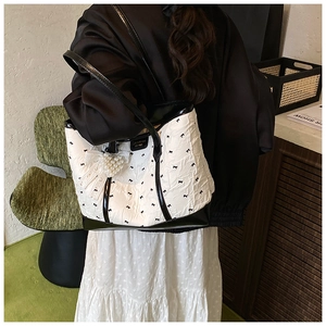 Détail du sac cabas matelassé blanc à nœuds noirs avec pendentif cœur en perles