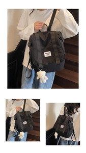 Close-up of black canvas backpack with waswac rules patch and plush bear accessory