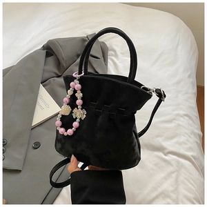 Detailed shot of a black pleated bucket bag featuring a purple beaded floral charm strap