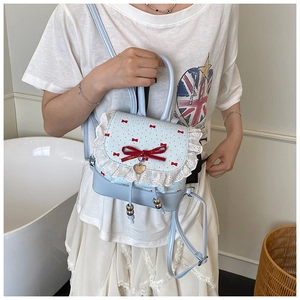 Detail of light blue PU backpack with white lace edges, red bows and heart charm