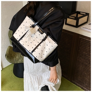 Détail du sac cabas rose avec imprimé nœud noir et breloque en dentelle de perles