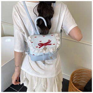 Detailed view of light blue lace mini backpack with red bows and heart pendant detail