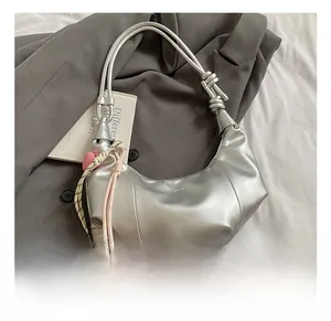 Détail du sac hobo argenté avec bandoulière en corde nouée et pendentif coeur rose