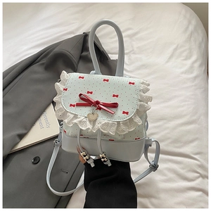 Close-up of light blue bag with lace trim, red bow details and heart-shaped pendant
