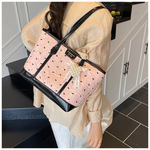 Détail du sac cabas matelassé rose avec nœuds noirs et pendentif en dentelle perlée