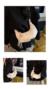 Détail du sac hobo crème avec bandoulière nouée et pendentif cœur rose élégant