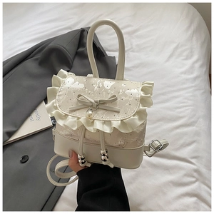 Detail of cream lace backpack with elegant ruffles, pearl charm, and chic bow decor