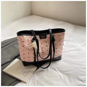 Détail d'un cabas plissé rose avec des motifs de nœuds noirs et des charms élégants en dentelle