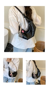 Détail du sac croissant noir avec bandoulière nouée et breloque en forme de cœur