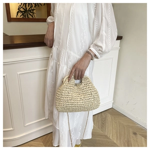 Detail of woven straw handbag featuring natural texture, wooden handle and gold chain strap