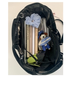 Spacious interior of a black satin tote bag showing books and a tablet in macro view