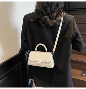 Chic cream mini crossbody bag with woven texture on a black suit back view
