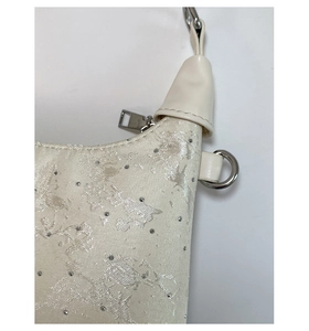 Detail of white jacquard fabric with floral patterns and sparkling crystal rhinestones