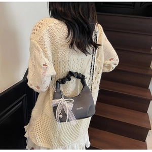 Détail du sac en tissu gris avec nœud en dentelle perlée et poignée plissée chic