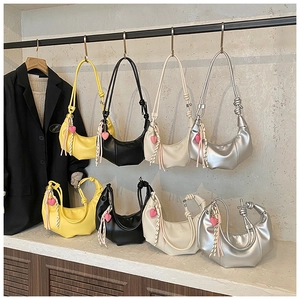 Détail d'un sac plissé en cuir avec un cœur rose décoratif et des glands à rayures