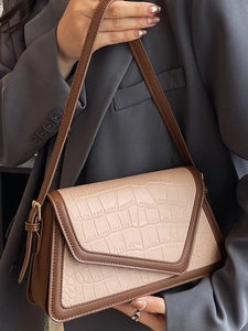Minimalist beige crocodile pattern shoulder bag with brown trim and geometric flap design