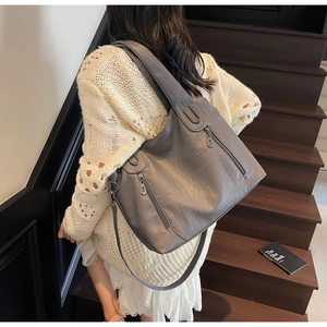 Detail of grey lychee leather tote bag featuring decorative zippers and sturdy handles