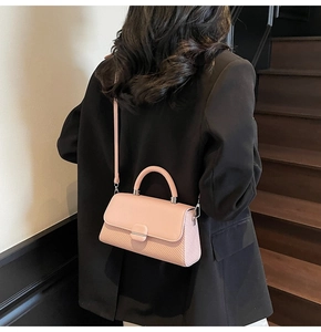 Pink crossbody bag with textured fabric surface and round handle shown on shoulder