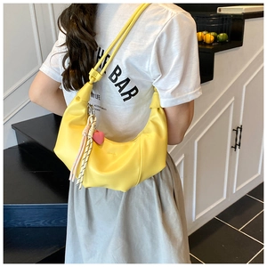 Détail d'un sac à bandoulière croissant jaune vif avec pendentif cœur et cordon