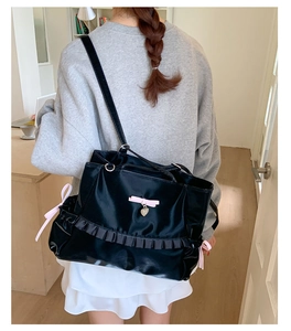 Detail of ruffled satin texture and pink bow accents on the black tote bag