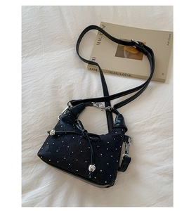 Detail of black pleated dumpling bag with white polka dots and silver metal drawstring beads