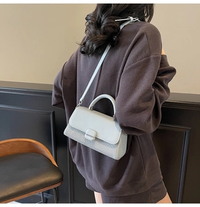 Detailed back view of a grey woven crossbody bag showing strap length and size on model