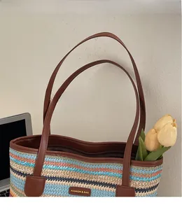 Gros plan d'un sac cabas tissé multicolore avec de longues anses et fermeture éclair