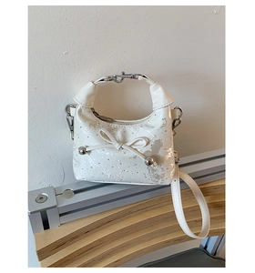 Close-up of white crescent bag featuring silver ink splashes and bow detail