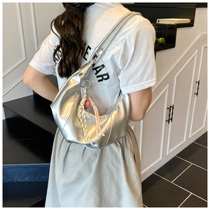 Détail du sac demi-lune argenté avec fini brillant et breloque en forme de cœur