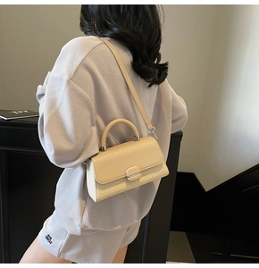 Detail of beige crossbody bag featuring textured weave design and gold metallic clasp