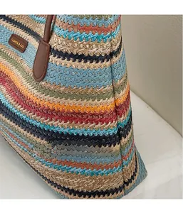 Détail du sac cabas tissé multicolore avec anse en cuir marron et écusson de mode gravé