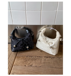 Detail of mini hobo bags featuring bow decoration and metallic bead charms on textured fabric