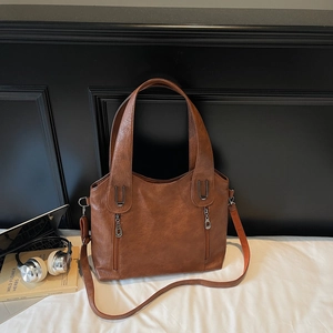 Detail of dark brown tote bag with premium lychee grain texture and metal zipper pockets