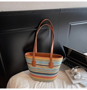 Detail der bunt gestreiften Strohtasche mit Regenbogenmuster und braunem Ledergriff