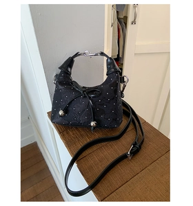 Close-up of black jacquard fabric texture with silver studs and leather bow detail