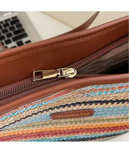 Détail d'un sac cabas tissé à rayures colorées avec fermeture éclair et étiquette cuir