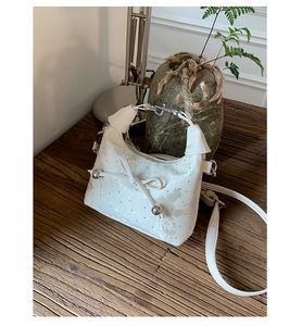 Detail of white PU leather handbag with metallic beads, bow design and silver hardware
