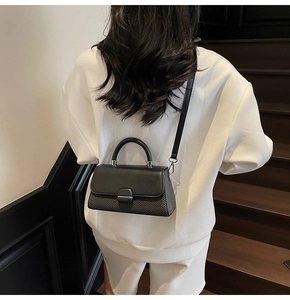 Detail of a black square crossbody bag with textured panel worn by a model in lifestyle setting