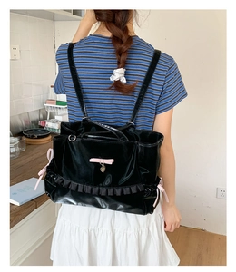 Detail of black faux leather bag with ruffle trim and pink bow in a lifestyle setting