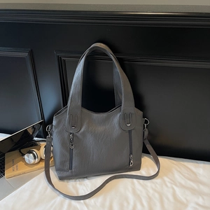 Detail of grey tote bag with wrinkled texture, vertical zippers, and adjustable strap