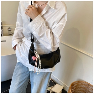 Detail of black semi-circle hobo bag with pink heart pendant and knot strap decoration