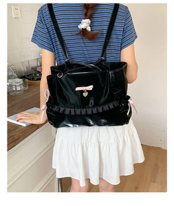 Detail of black patent leather bag with pink bows and elegant ruffled edge trim